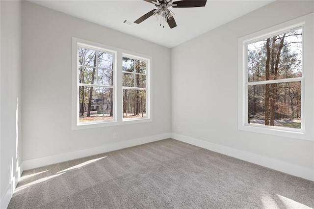 spare room featuring carpet floors, visible vents, baseboards, and a ceiling fan