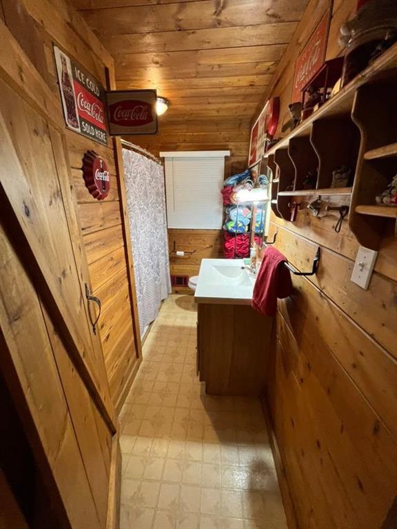 full bath featuring toilet, wood ceiling, wood walls, vanity, and tile patterned floors