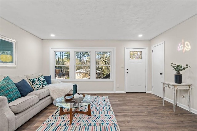 living room featuring a textured ceiling, baseboards, wood finished floors, and recessed lighting