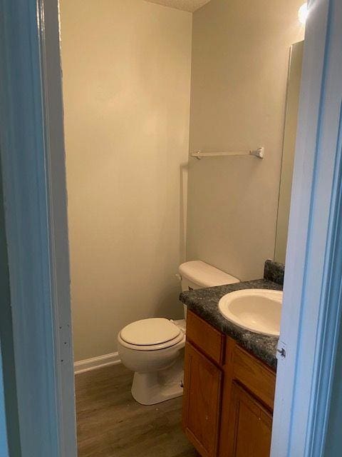 bathroom with wood-type flooring, toilet, vanity, and a textured ceiling