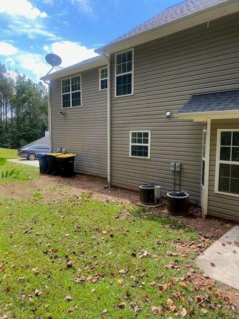 view of property exterior with a yard and central air condition unit