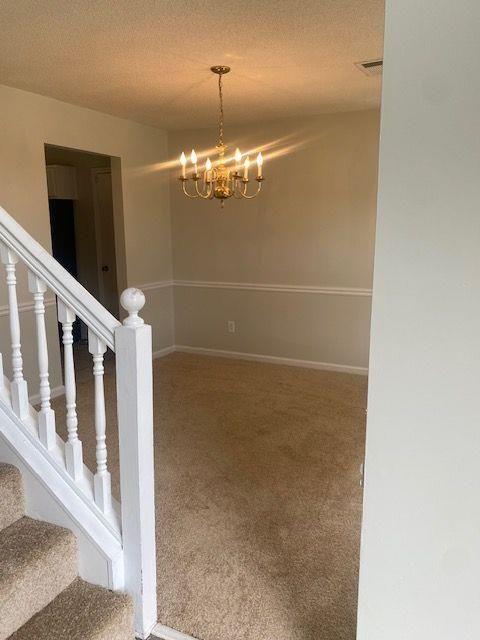 stairway with a textured ceiling, a chandelier, and carpet