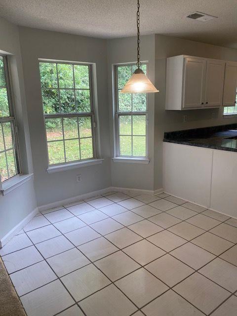 unfurnished dining area featuring light tile patterned flooring, a healthy amount of sunlight, and a textured ceiling