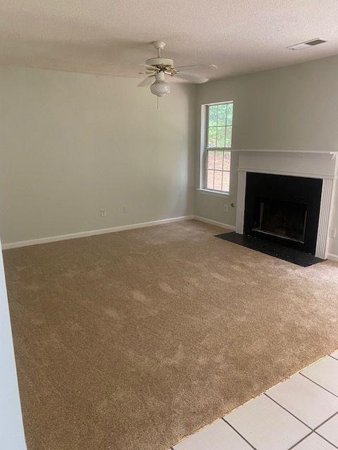 unfurnished living room with ceiling fan, a textured ceiling, and carpet