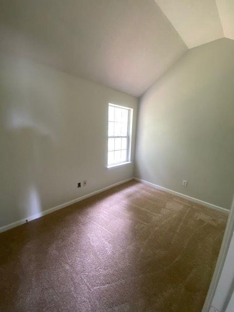 empty room with lofted ceiling and carpet floors