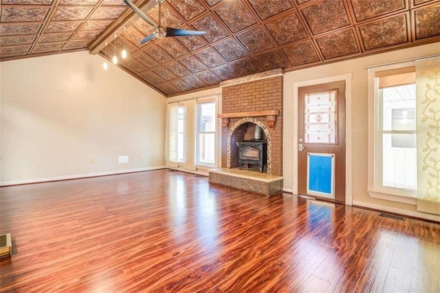 unfurnished living room with vaulted ceiling with beams, ceiling fan, wood-type flooring, and a wood stove