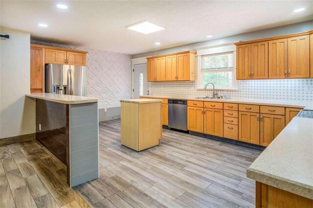 kitchen featuring sink, a kitchen island, light hardwood / wood-style floors, and appliances with stainless steel finishes