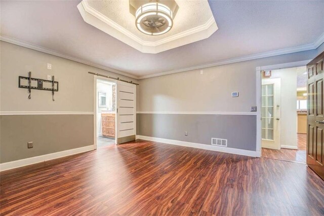 empty room featuring ornamental molding, a raised ceiling, ceiling fan, and dark wood-type flooring