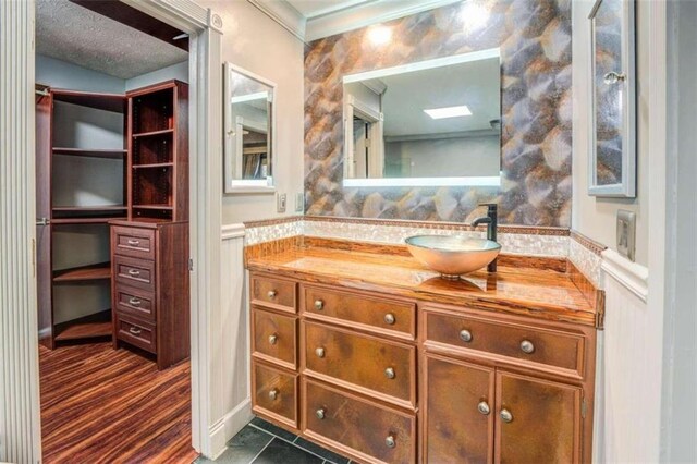 bathroom featuring hardwood / wood-style floors, vanity, ornamental molding, and a textured ceiling