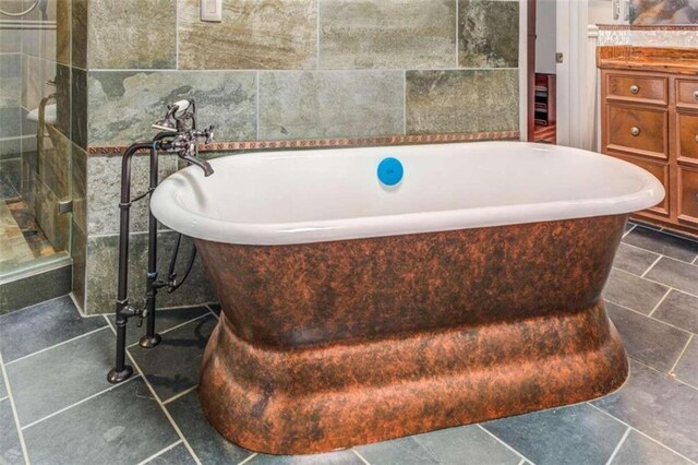 bathroom featuring a washtub, vanity, and tile walls