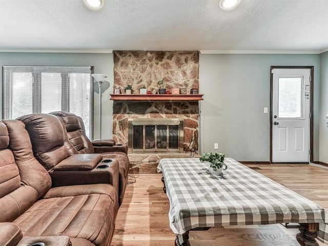 living room featuring ornamental molding, a fireplace, a textured ceiling, and light wood-type flooring