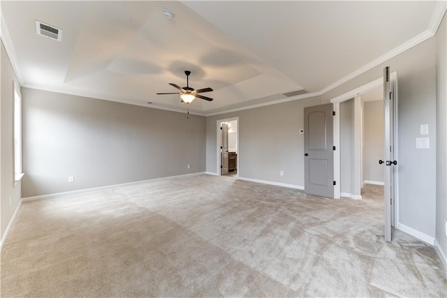 carpeted empty room with a raised ceiling, ceiling fan, and ornamental molding