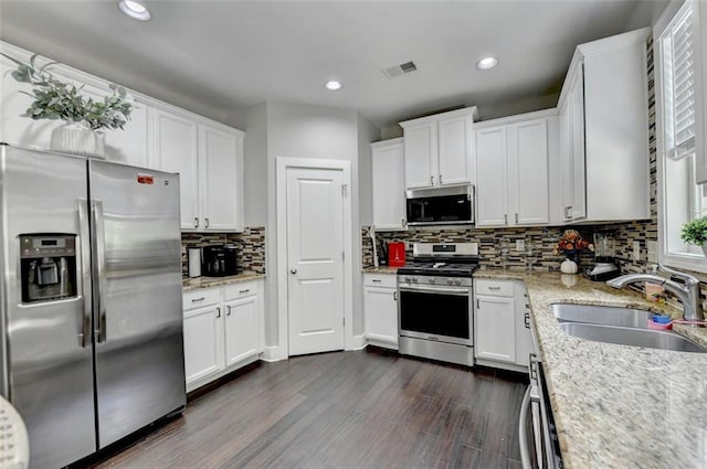 kitchen featuring sink, stainless steel appliances, light stone countertops, dark hardwood / wood-style floors, and white cabinets