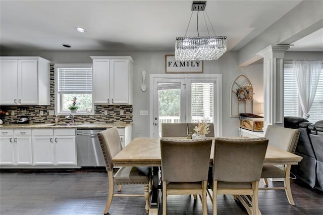 dining space featuring an inviting chandelier, sink, decorative columns, and dark hardwood / wood-style floors