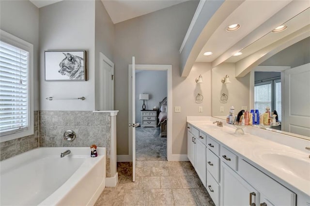 bathroom featuring lofted ceiling, a bathtub, and vanity