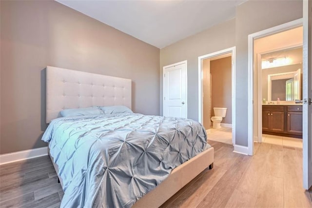 bedroom with connected bathroom, light hardwood / wood-style floors, and sink