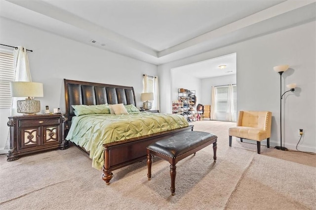 carpeted bedroom with a tray ceiling