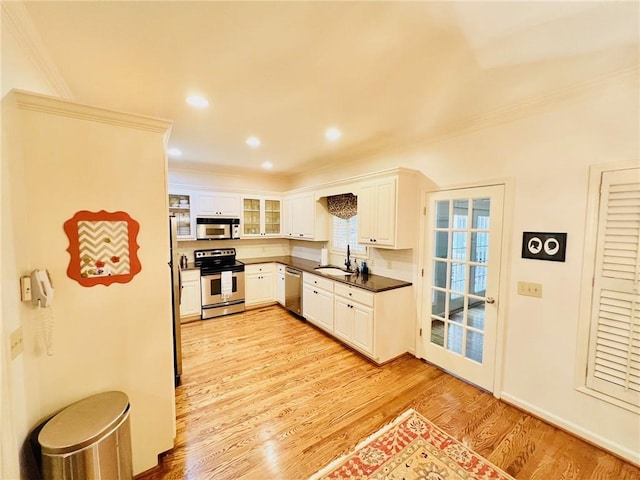 kitchen featuring sink, white cabinetry, stainless steel appliances, crown molding, and light hardwood / wood-style floors