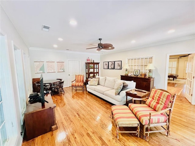 living room featuring light hardwood / wood-style flooring, ceiling fan, and crown molding