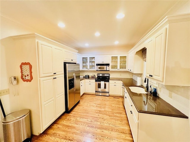 kitchen with light hardwood / wood-style floors, tasteful backsplash, sink, white cabinets, and appliances with stainless steel finishes