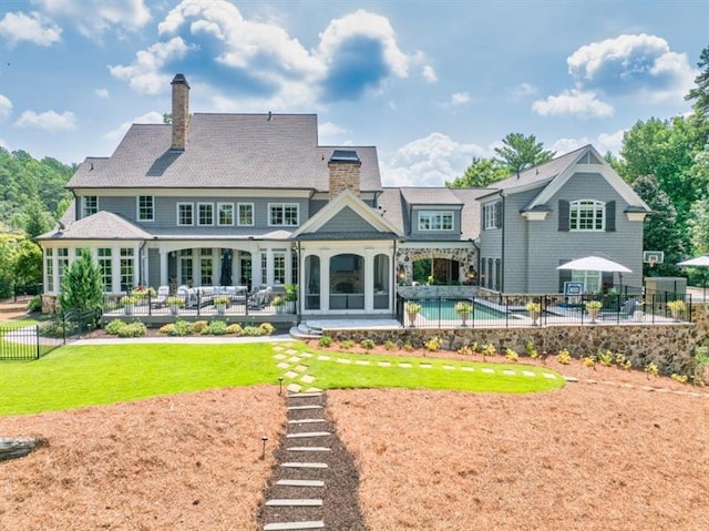 rear view of house featuring a patio, fence, a fenced in pool, a yard, and a chimney