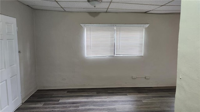 unfurnished room with a paneled ceiling and dark hardwood / wood-style flooring