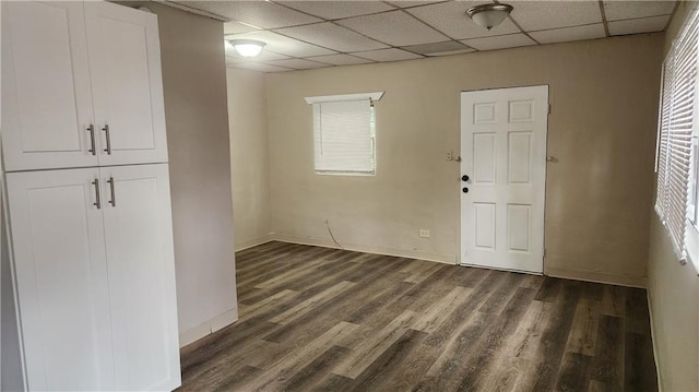 interior space with a paneled ceiling and dark hardwood / wood-style flooring