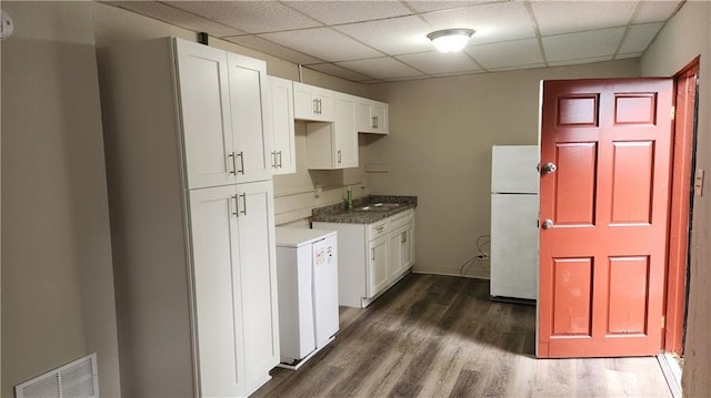 kitchen with white cabinetry, dark hardwood / wood-style floors, a drop ceiling, and white refrigerator