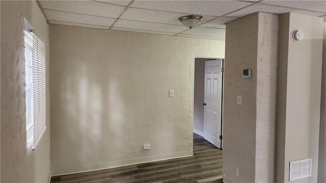 empty room featuring a paneled ceiling and dark hardwood / wood-style flooring