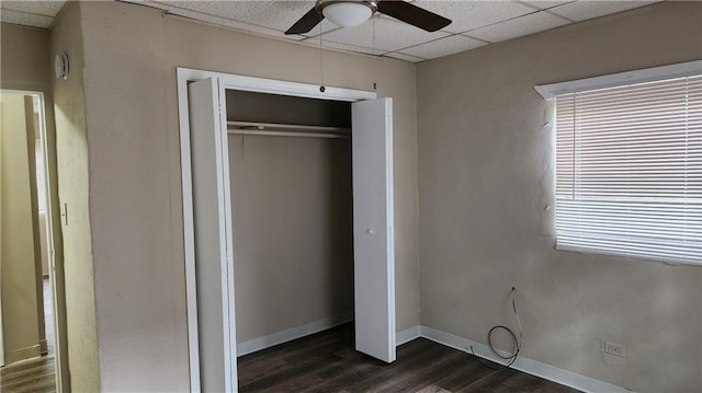 unfurnished bedroom featuring dark hardwood / wood-style floors, a paneled ceiling, a closet, and ceiling fan