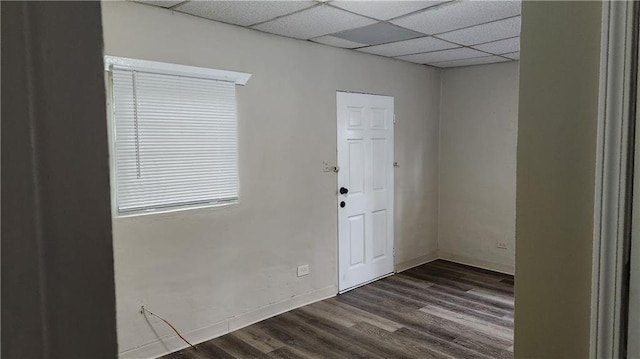 unfurnished room with dark hardwood / wood-style flooring and a drop ceiling