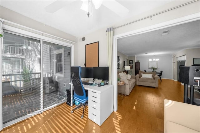 home office featuring ceiling fan with notable chandelier, ornamental molding, wood finished floors, and visible vents