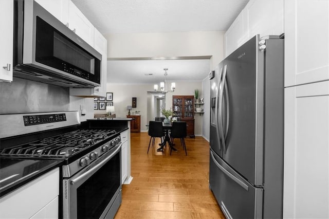 kitchen with crown molding, stainless steel appliances, and white cabinets