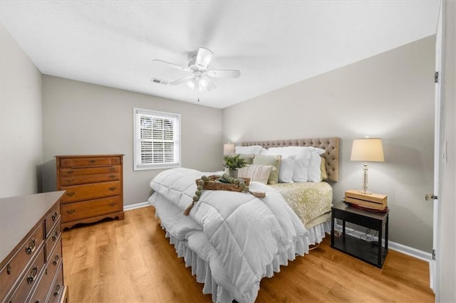 bedroom featuring light wood-style flooring, a ceiling fan, visible vents, and baseboards