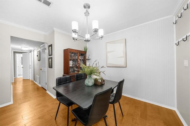 dining room with ornamental molding, baseboards, visible vents, and light wood finished floors