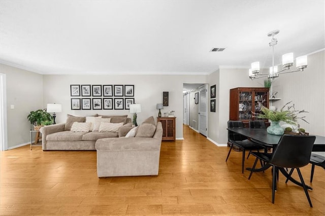 living room with an inviting chandelier, ornamental molding, and light hardwood / wood-style flooring