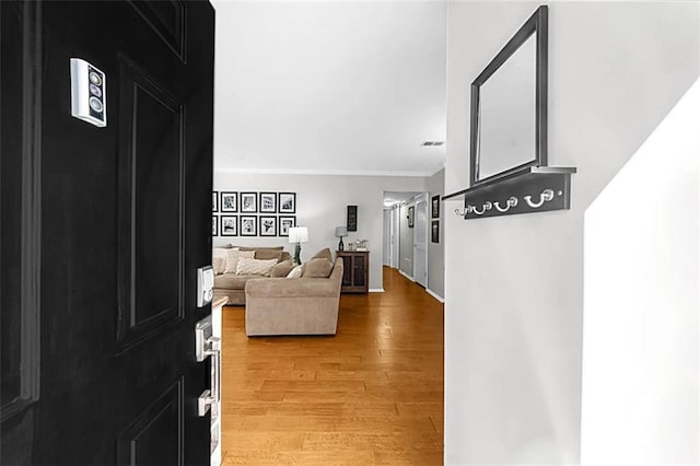 foyer entrance featuring crown molding, light wood finished floors, and baseboards