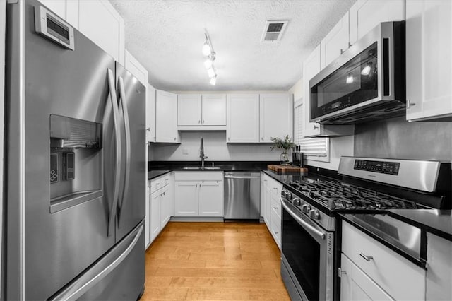 kitchen with visible vents, appliances with stainless steel finishes, white cabinets, and a sink