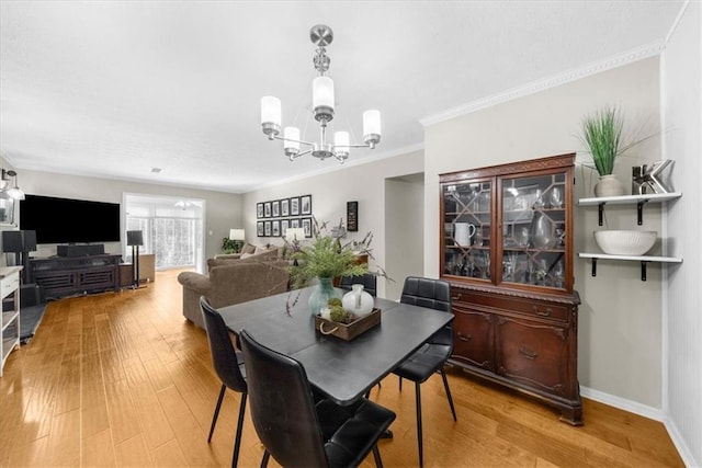 dining area featuring a chandelier, ornamental molding, baseboards, and light wood-style floors