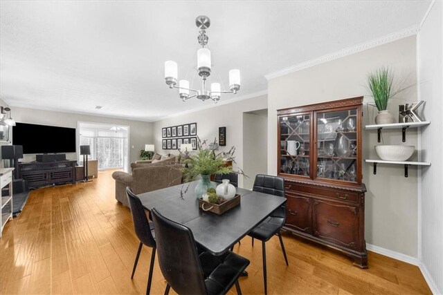 dining room with a chandelier, light wood-style floors, crown molding, and baseboards
