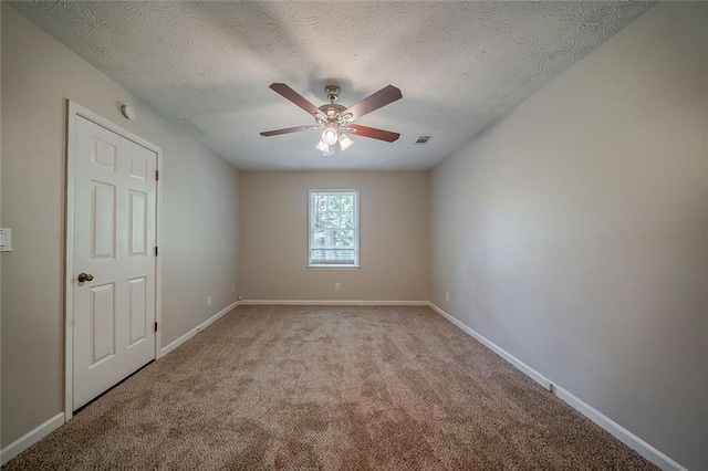 spare room featuring a ceiling fan, a textured ceiling, visible vents, baseboards, and light carpet