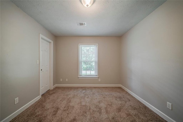 carpeted spare room featuring baseboards, a textured ceiling, and visible vents