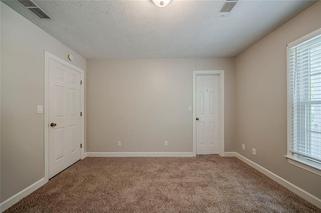 empty room with visible vents, light colored carpet, and a wealth of natural light