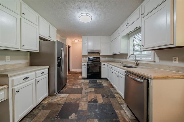 kitchen with white cabinets, stainless steel appliances, stone finish floor, and a sink