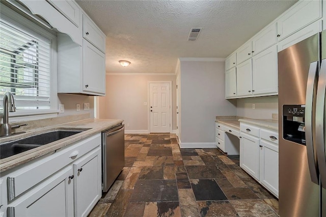kitchen featuring white cabinets, stainless steel appliances, stone finish flooring, and a sink