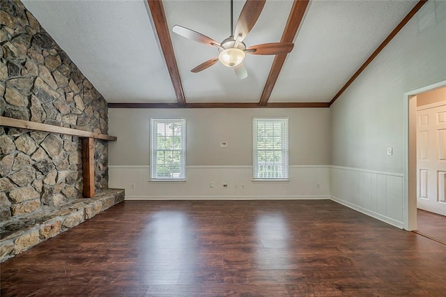 unfurnished living room with vaulted ceiling with beams, a ceiling fan, wainscoting, and wood finished floors