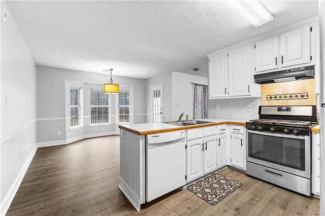 kitchen with a peninsula, a textured ceiling, dishwasher, under cabinet range hood, and stainless steel gas stove