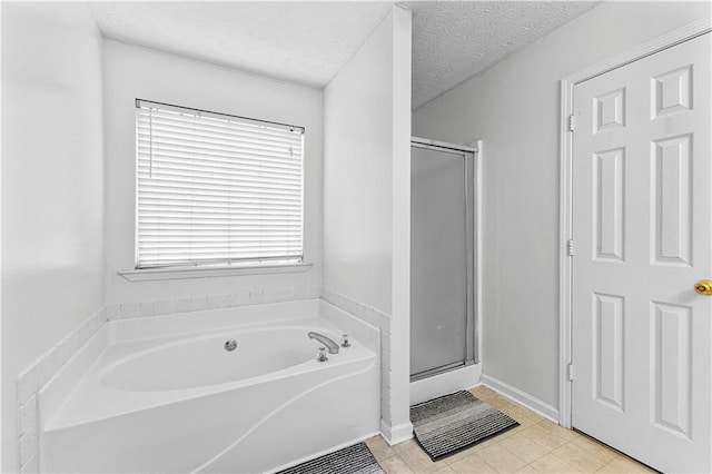 bathroom featuring a textured ceiling, a shower stall, a garden tub, and tile patterned floors