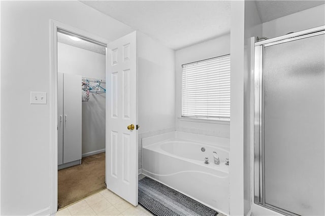 full bath featuring baseboards, a bath, a textured ceiling, and a stall shower