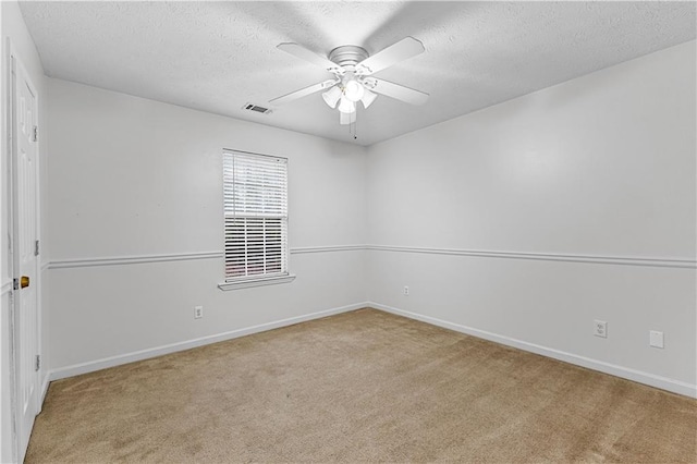 carpeted spare room featuring a textured ceiling, a ceiling fan, baseboards, and visible vents